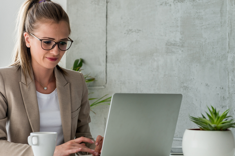 White woman with glasses and short hair working at a desktop computer.