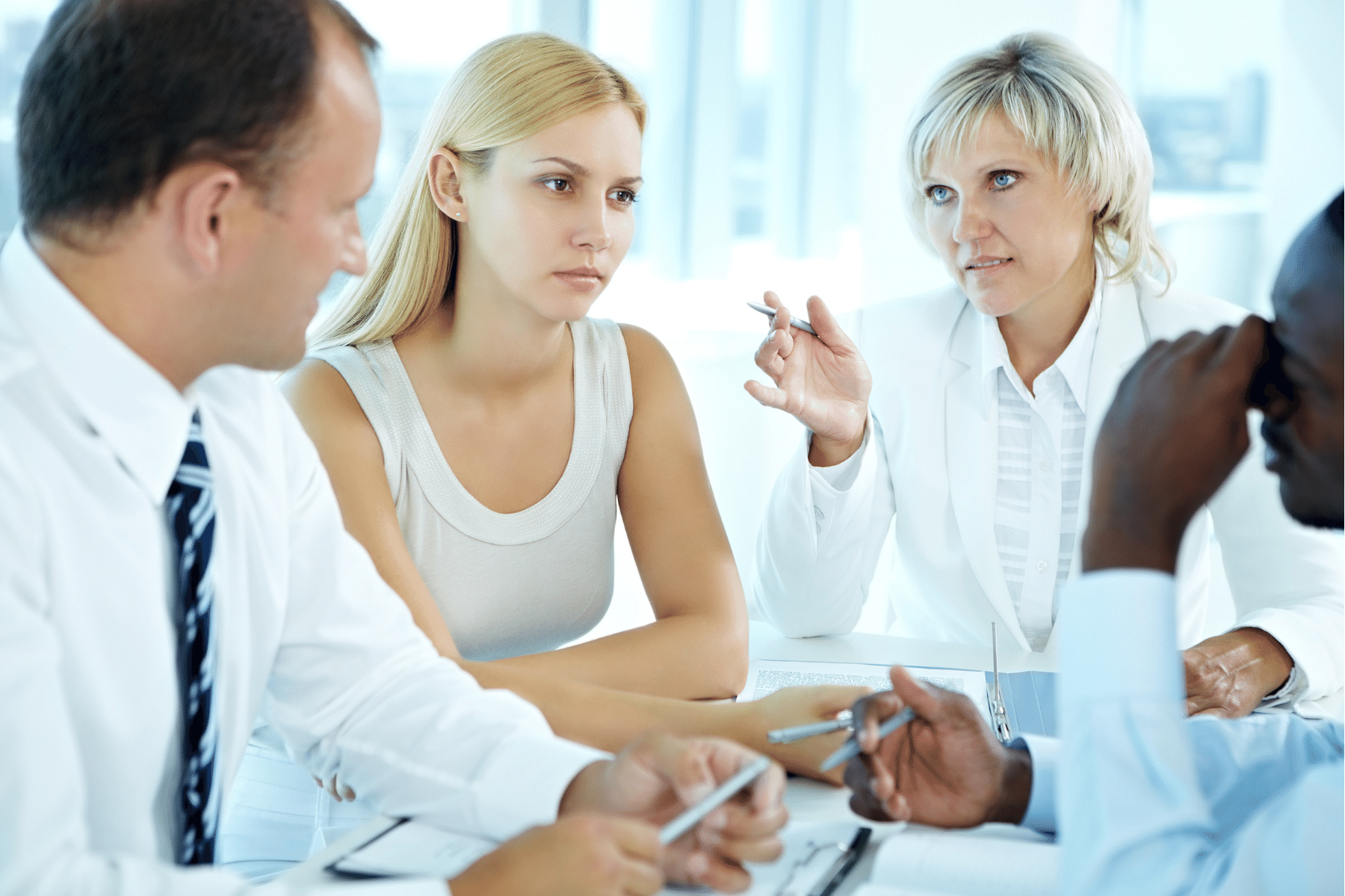 woman worriedly looks at two work colleagues who seem to talking about her.