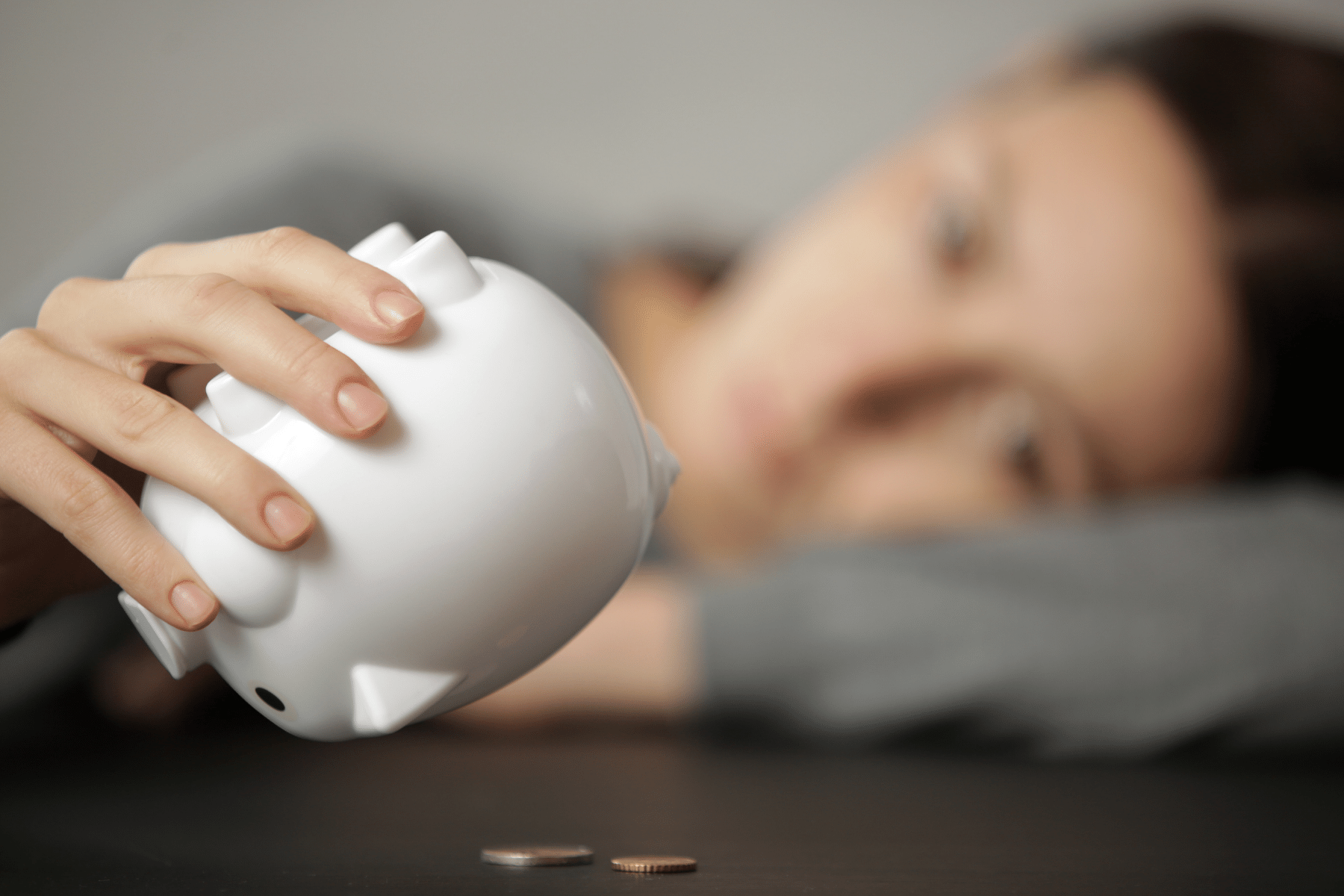 blurred out student holding a piggy bank dumping out coins