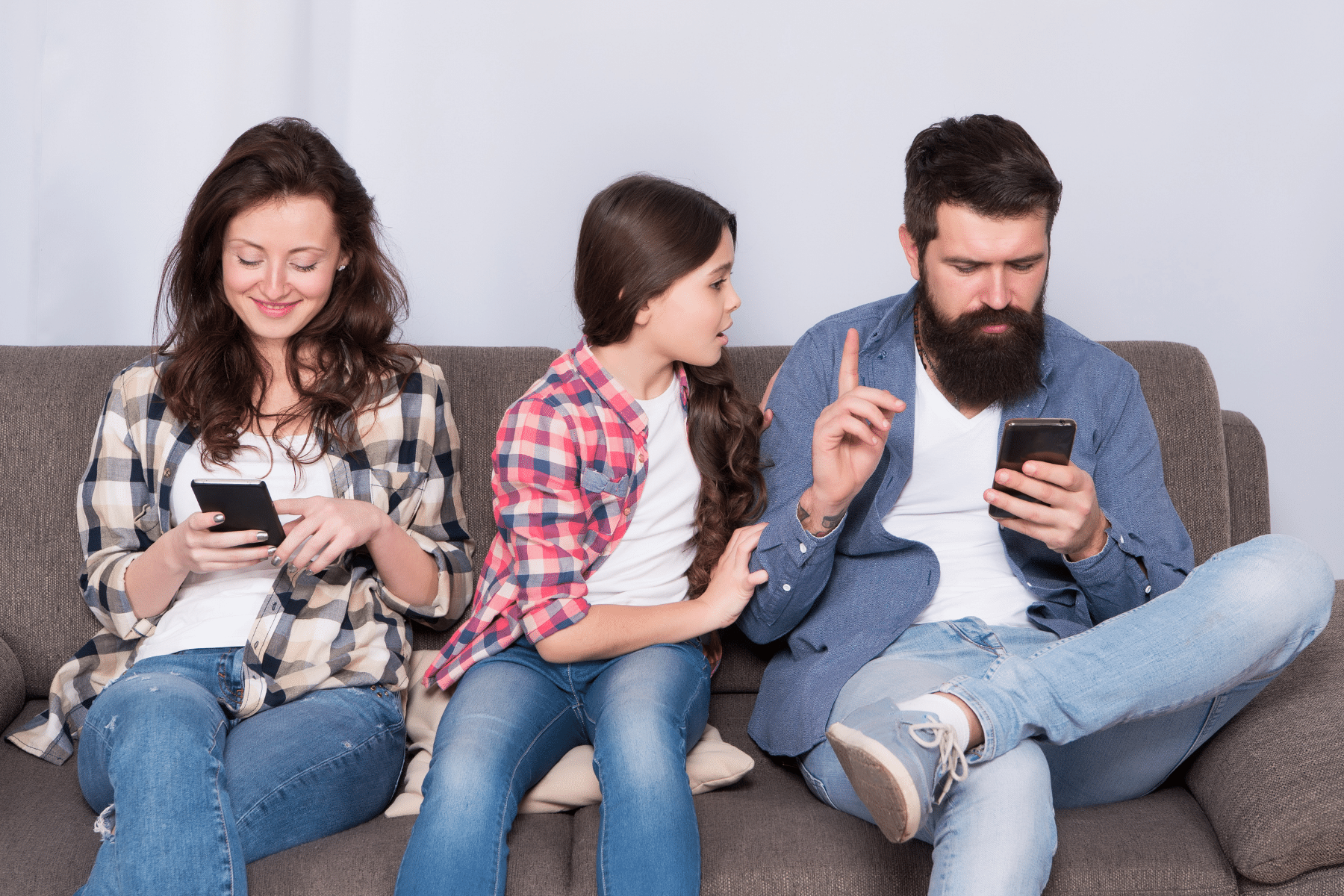 Two parents sitting with a child, both parents on their phones not paying attention