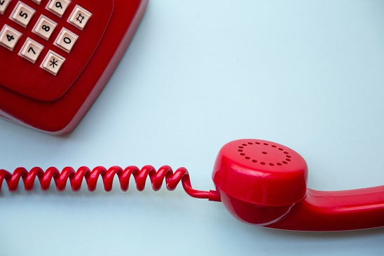 Red corded phone off the hook sitting on a table